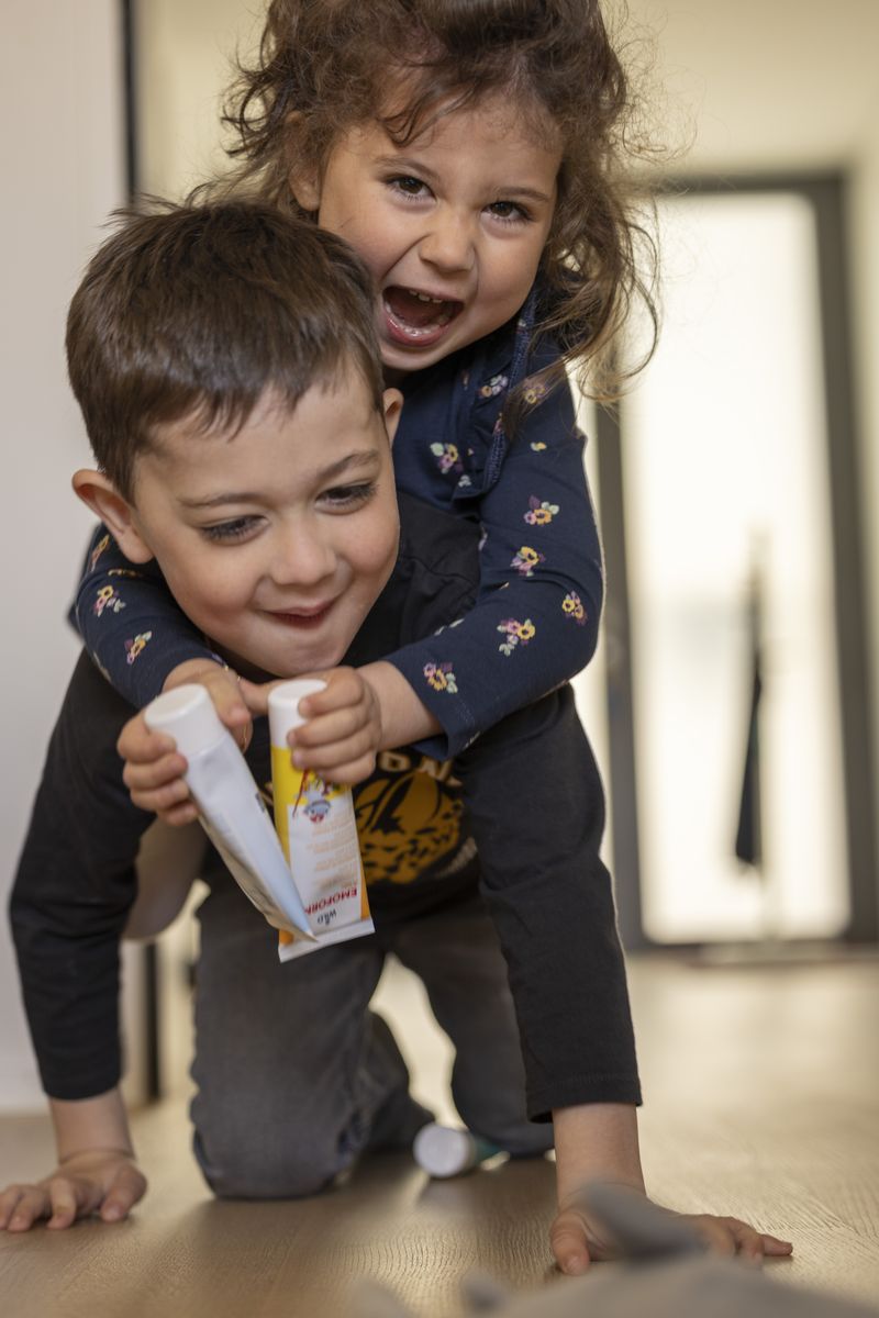 A child laughing, holding a tube of Wild toothpaste